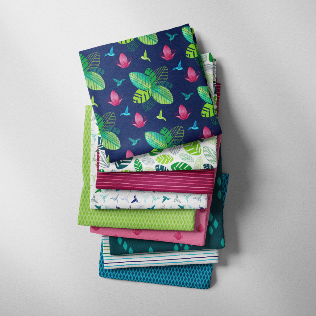 A pile of fabric in various patterns from The Rainforest Joy collection
