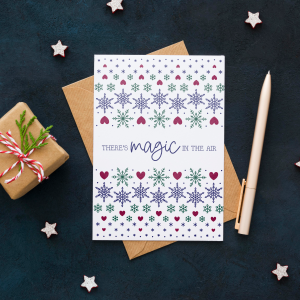 Christmas greetings card featuring the Fairisle Snowflake pattern by The Unicorn Factory and the text There's Magic In The Air