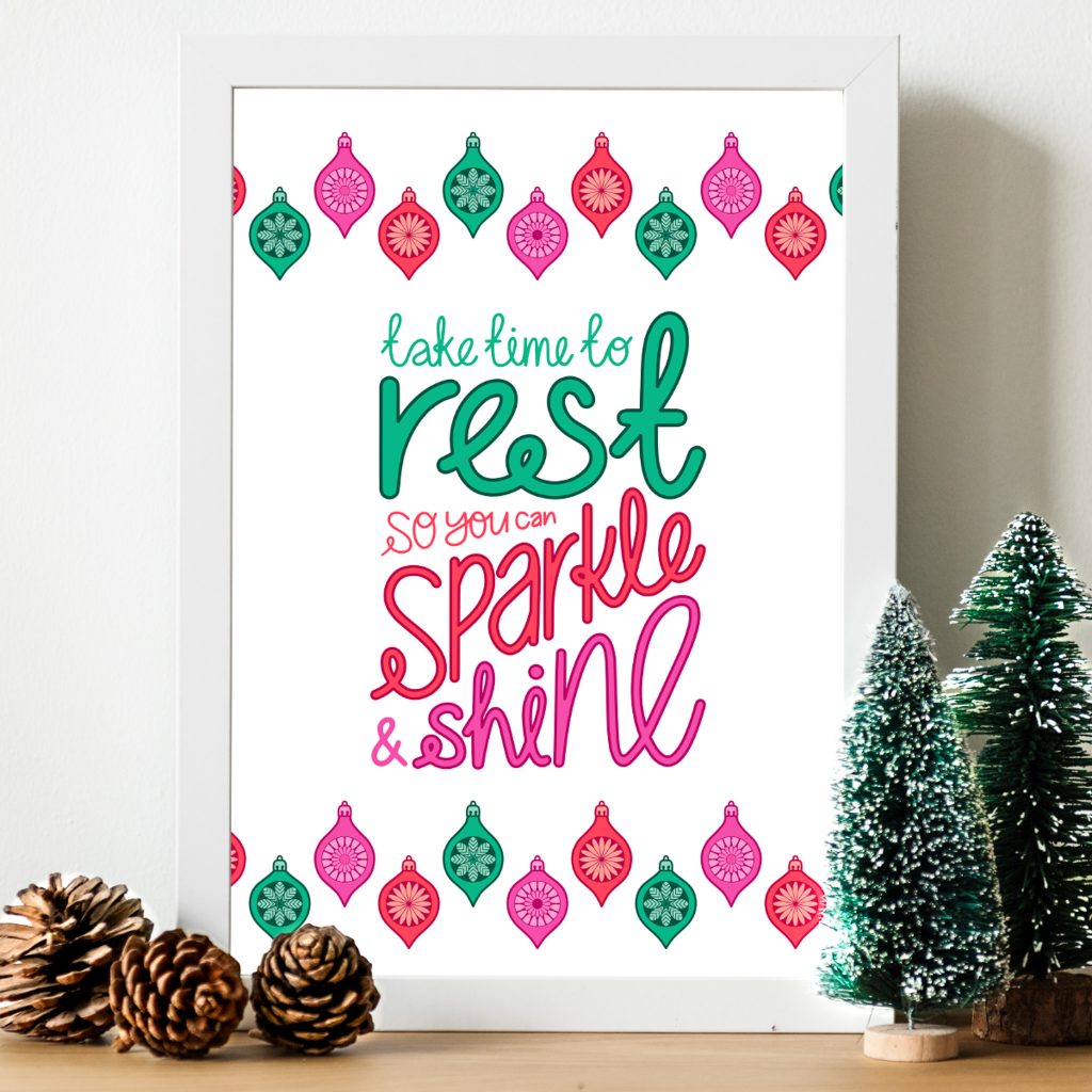 Mock up of an art print in a white frame leaning against a white wall. The art print has an illustrated quote "Take time to rest so you can Sparkle & Shine" with a bauble border above and below the quote, on a plain white background.
